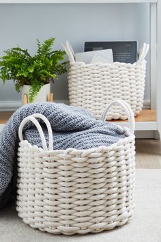 two white wicker baskets sitting next to each other on a rug in front of a fireplace