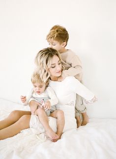 a woman sitting on top of a bed holding a child