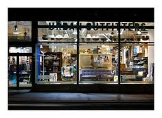 a store front with many items displayed in it's windows and lit up at night