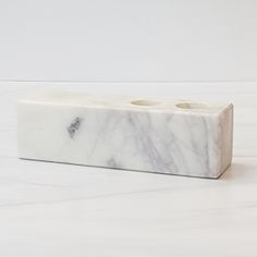 a white marble block with two candles on the top and one candle holder in the middle