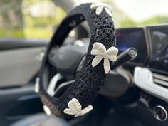 the steering wheel is decorated with bows and crocheted fabric in black, white and silver