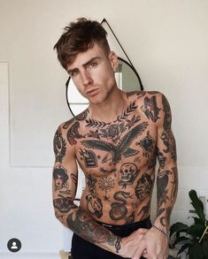 a man with many tattoos on his chest and arms sitting in front of a mirror