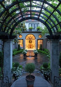 an outdoor patio with potted plants and lights on the door way to a house