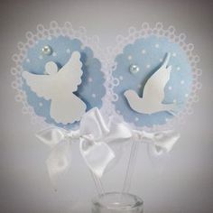 two small vases with white and blue paper angel decorations in them on a table