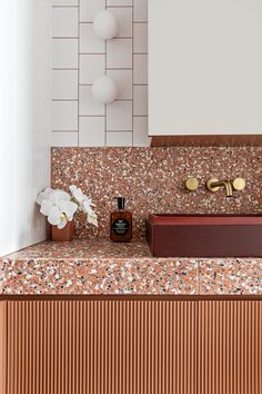 a bathroom sink sitting under a mirror next to a vase with flowers