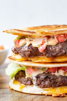 two hamburgers stacked on top of each other with cheese and tomato slices around them