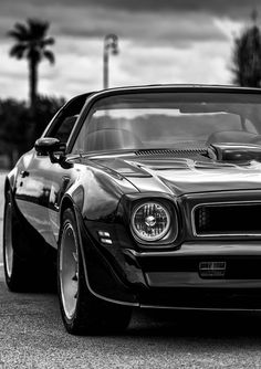 a black and white photo of the front end of a muscle car parked in a parking lot