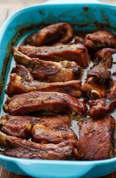 some meat is in a blue casserole on a wooden table and ready to be cooked