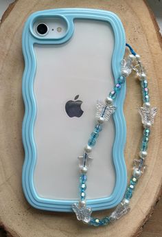 an iphone case with pearls and glass beads on the front is sitting on a piece of wood