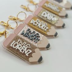 four key chains with different types of tags attached to them, one is pink and the other is gold