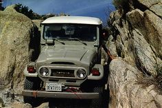 an old truck is parked in the rocks