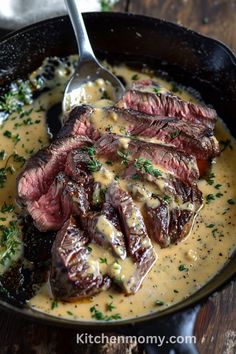 steak and gravy in a cast iron skillet with a spoon on the side