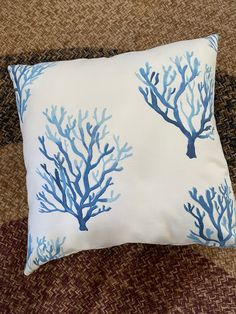 a pillow with blue corals on it is sitting on a brown couch next to a chair