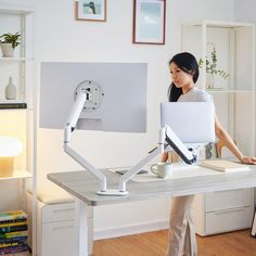 a woman standing in front of a desk with a monitor and keyboard attached to it