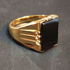 Gold-plated stainless steel. This is a men's style ring with a black flat rectangle simulated onyx stone.  You will look so stylish wearing this affordable and eye-catching ring! The front of the ring is 17mm tall. The black glass stone is 16 x 11.5 mm. Stainless steel jewelry is durable, affordable and TUSK stainless steel is specially treated to equal the brightness and shine of sterling silver and platinum. It is hypoallergenic, extremely resistant to rust, scratching, corrosion and tarnishing.  The gold-plated stainless steel is beautiful and so affordable compared to a solid gold ring. See our other men's statement rings here https://www.etsy.com/shop/BlueMoonTrader?section_id=28033723 and check back as we're going through our whole stash and listing new items weekly. ◄ SHIPPING ►  Sh Black Stone Ring For Men, Stone Rings For Men, Black Stone Ring, Mens Gold Rings, Golden Ring, Solid Gold Rings, Mens Gold, Onyx Stone, Black Stone