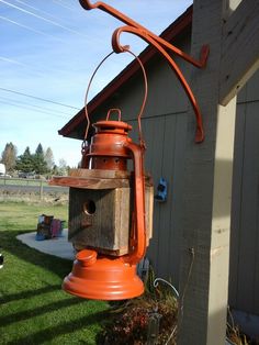 an orange birdhouse hanging from the side of a house