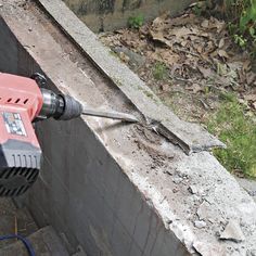 an electric driller is being used to remove debris from the side of a building