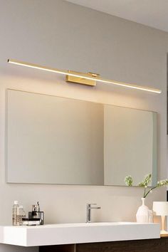 a bathroom with a sink, mirror and lights on the wall above it's counter