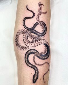 a black and white snake tattoo on the leg, with an intricate design around it