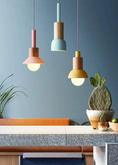 several different colored lights hanging from the ceiling above a table with plants and bowls on it