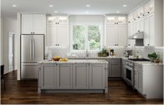 a large kitchen with white cabinets and wood floors