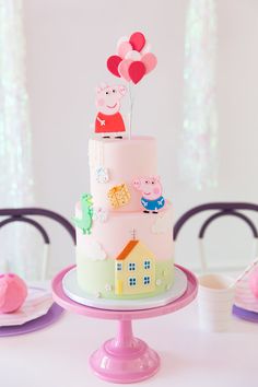 a peppa pig birthday cake on a table with pink plates and balloons in the air