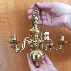 a person is holding a brass chandelier