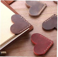 leather heart shaped magnets sitting on top of a wooden table next to a notebook