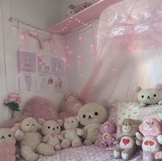 a bunch of stuffed animals sitting on a bed in a room with pink lights strung from the ceiling