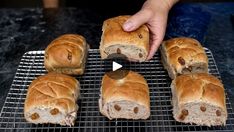 a person is cutting some bread on a cooling rack with other pastries in front of them