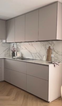 a kitchen with marble counter tops and gray cabinets