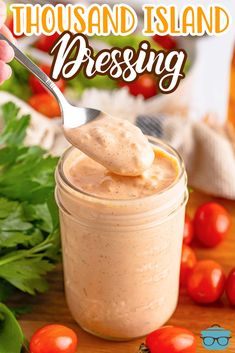 a spoon full of dressing sitting on top of a table next to tomatoes and parsley