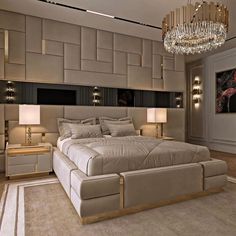 a large bed sitting inside of a bedroom under a chandelier