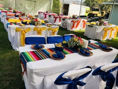 an outdoor event set up with colorful table cloths and plates on the tables for guests to eat