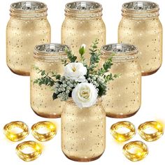 four jars with flowers in them sitting next to gold coins