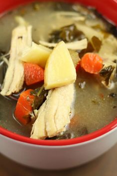 a red bowl filled with soup on top of a wooden table