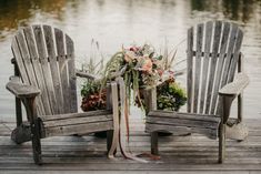 two wooden chairs sitting on top of a dock