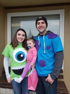 a man and woman standing next to a child in front of a door wearing costumes