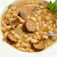 a white bowl filled with beans and sausage