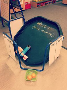 a blackboard with writing on it and some oranges in a green bowl next to it