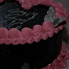 a black cake with pink frosting and a butterfly on top