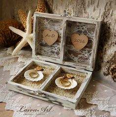 two wedding rings in an open box on a lace tablecloth with shells and starfish