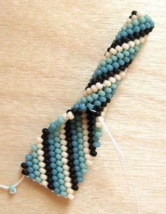 a beaded bracelet with black, white and blue beads hanging from it's side