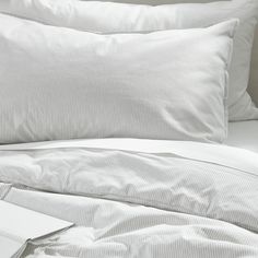 an unmade bed with white sheets and pillows on top of it, next to a book