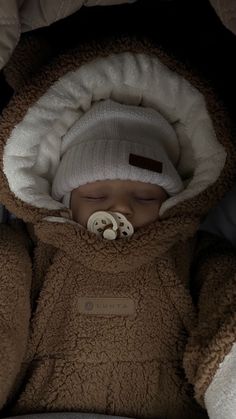 a baby sleeping in a car seat wearing a teddy bear outfit