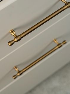 two brass handles on the side of a white cabinet