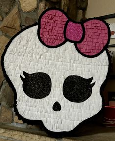 a paper mache with a pink bow on it's head is displayed in front of a stone wall