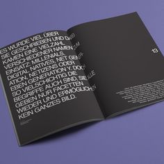 an open book with black and white text on the front cover, sitting on a purple surface