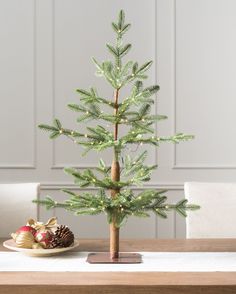 a small christmas tree sitting on top of a wooden table next to a pine cone