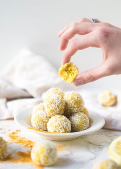 a person is picking up some food from a white plate with lemons on it